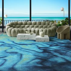 a living room filled with furniture next to a large window overlooking the ocean on a sunny day