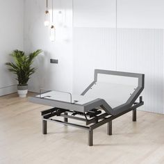 an adjustable bed frame in the middle of a room with white walls and wood flooring