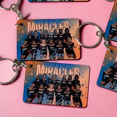 four keychains with photos of the same team and name on them, all in different colors