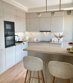 two stools are in front of the kitchen counter and bar area with white cabinets