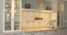 a large kitchen with white cabinets and marble counter tops, along with glass doors that lead to the dining room