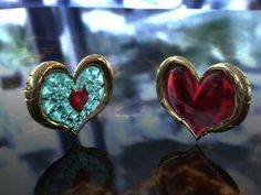 two heart shaped earrings sitting on top of a glass table next to another pair of red and green hearts