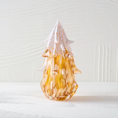 a small glass vase sitting on top of a white table next to a wooden wall