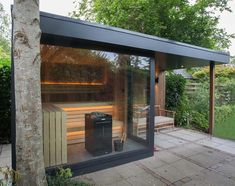 an outdoor sauna with wooden benches and hot tub in the back ground, surrounded by trees