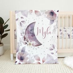 a baby crib with a purple and white flowered blanket