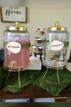 two large jars filled with cupcakes on top of green moss covered trays