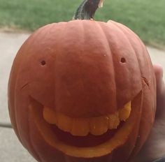 a person holding up a carved pumpkin