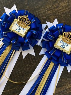 two blue and white ribbons with gold crowns on them, one for the first time