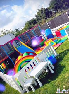 there are many different colored chairs in the yard and one has a rainbow theme on it