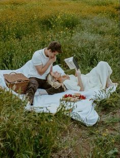 a man and woman laying on a blanket in the grass