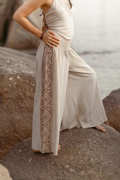 Introducing the Ragini Pants, a harmonious blend of comfort, style, and cultural charm. These wide-leg pants are crafted from soft cotton fabric, ensuring a lightweight and breathable feel that keeps you cool and relaxed throughout the day. In a serene natural color, they embody simplicity and versatility, perfect for casual outings. Adding a touch of traditional artistry, the Ragini Pants feature intricate block prints delicately adorning the sides. These block prints not only enhance the pants' aesthetic appeal but also celebrate the beauty of handcrafted designs rooted in cultural heritage. Each detail reflects a commitment to craftsmanship and timeless elegance. Designed for effortless elegance and everyday wear, the Ragini Pants offer a flattering silhouette with their wide-leg, provi Summer Beach Harem Pants Ankle-length, Ankle-length Harem Pants For Summer Beach, Ankle-length Summer Harem Pants For Beach, Summer Beach Ankle-length Harem Pants, Summer Vacation Ankle-length Harem Pants, Beige Harem Pants For Beach, Ankle-length Wide Leg Pants For Summer Beach, Beige Beach Pants With Loosely Fitted Hips, Beige Harem Pants For Beach In Summer