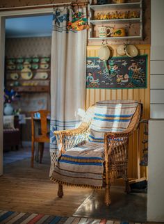 a wicker chair sitting in front of a window next to a wall with pictures on it