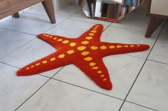 a red and yellow starfish rug on the floor next to a wooden table with a mirror