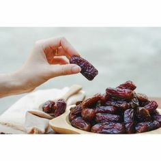 a person is picking up dates from a wooden plate