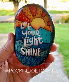 someone is holding up a painted rock with the words let your light shine on it