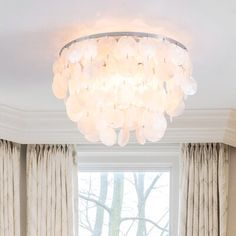 a living room filled with furniture and a chandelier hanging from the ceiling next to a window