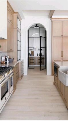 a kitchen with wooden cabinets and marble counter tops, along with an arched doorway leading to the dining room