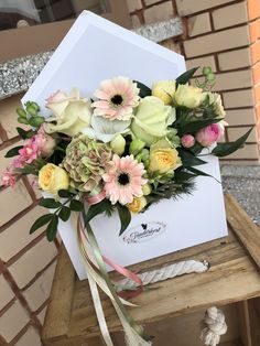 a bouquet of flowers sitting on top of a wooden table next to a white envelope