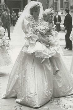 an old black and white photo of two women in wedding dresses, one holding a child