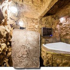 a bathroom with stone walls and a large bathtub in the corner next to a television