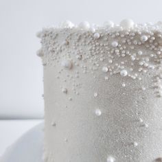 a close up of a white frosted cake with pearls on it's side