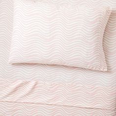 the pink and white bedding has wavy waves on it, as well as two pillows