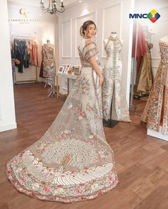 a woman standing in front of a dress on display at a store with mannequins behind her