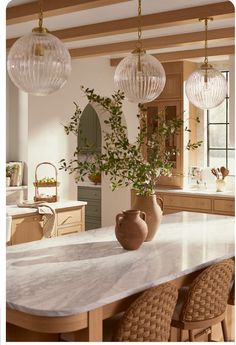 a kitchen with marble counter tops and hanging lights