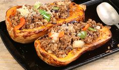 three stuffed sweet potatoes with meat and vegetables on a black serving tray next to garlic