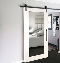 an open door leading to a bedroom with a bed in the background and a mirror on the wall