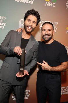 two men standing next to each other in front of a red carpet with the words people's choice awards on it