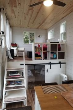 a loft with stairs leading up to the top floor and bookshelves on each side