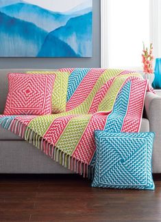 a living room with a couch covered in colorful pillows and blankets on top of it