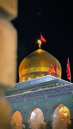 the dome of a building with red flags flying in the air above it at night