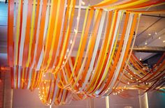 orange and white streamers hanging from the ceiling in a room with lights on it