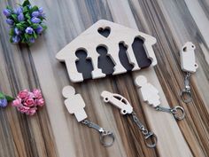 wooden keychains with cutouts of people in front of a house and flowers