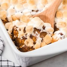 a casserole dish filled with marshmallows and topped with a wooden spoon