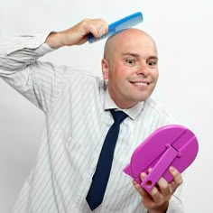 a balding man holding a purple object in his right hand and looking at the camera