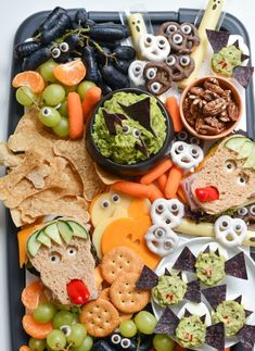 a tray filled with crackers, vegetables and other snacks to be eaten for halloween