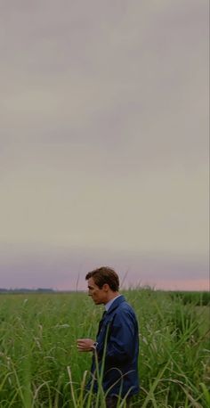 a man standing in the middle of a field looking at something on his cell phone