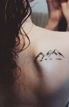 a woman with a mountain tattoo on her chest holding a cell phone to her ear