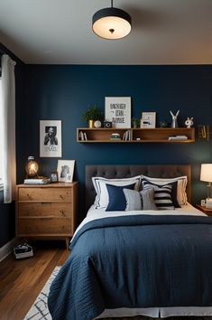 a bedroom with dark blue walls and white bedding, wooden shelves above the bed