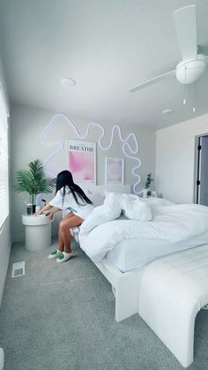 a woman sitting on top of a white bed in a bedroom