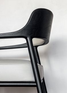 a black and white chair sitting on top of a white floor next to a wall