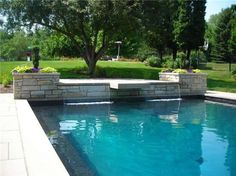 an outdoor swimming pool surrounded by landscaping and trees