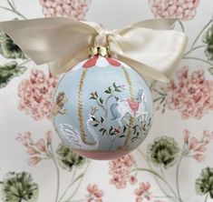 an ornament with a bow hanging from it's side on a floral wallpaper