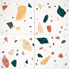 four pieces of broken glass sitting on top of a white tile floor with different colors and shapes