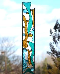 a stained glass window hanging from the side of a building with trees in the background