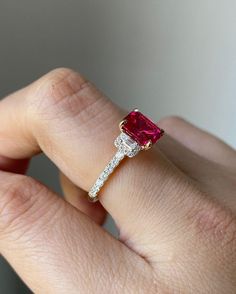 a woman's hand holding an engagement ring with a pink tourmaline stone