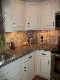 a kitchen with white cabinets and granite counter tops